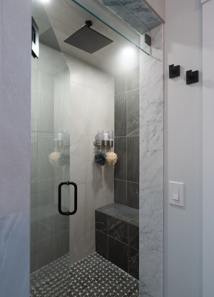 Luxury spa bathroom with glass soaking tub and stone tile walls by Serenity Baths in Goffstown NH